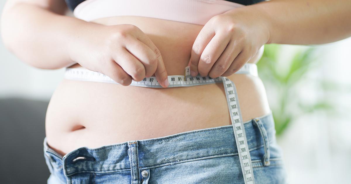 Fettleibige Frau misst Ihren Taillenumfang mit einem Maßband