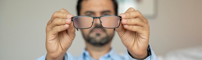 Mann mit schlechter Sehkraft richtet seine Brille.