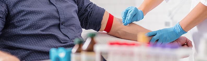 Eine Krankenschwester bereitet einen männlichen Patienten auf die Blutabnahme vor.