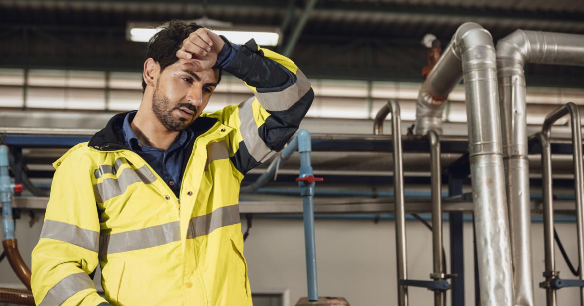 Mann hält sich vor Müdigkeit an der Stirn bei der Arbeit