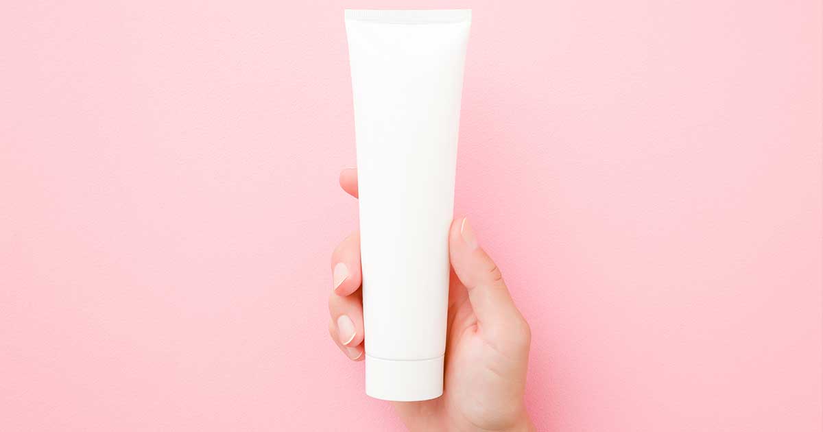 Hånd, der holder en tube creme