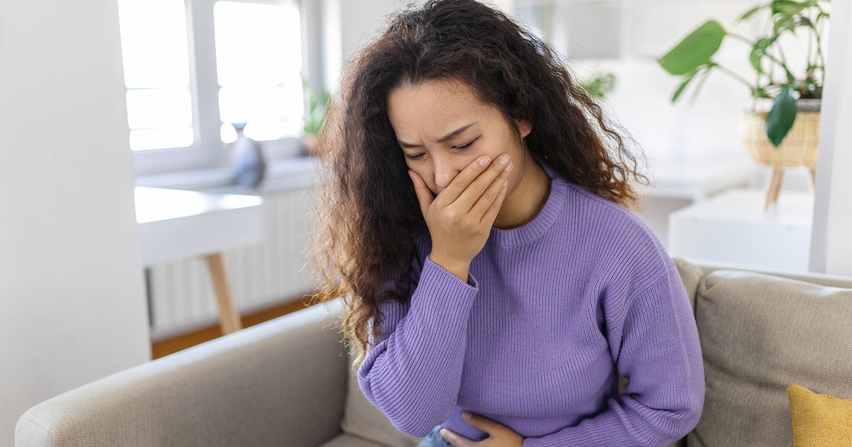 A woman feeling nauseous and clutching her stomach