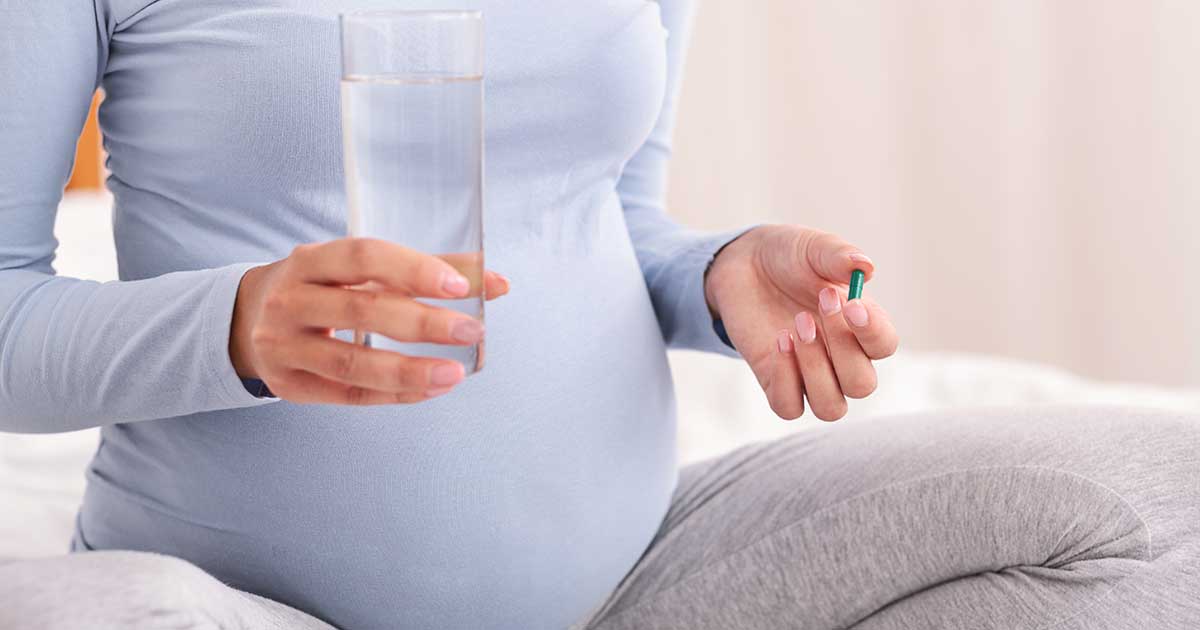 Pregnant woman holding a pill