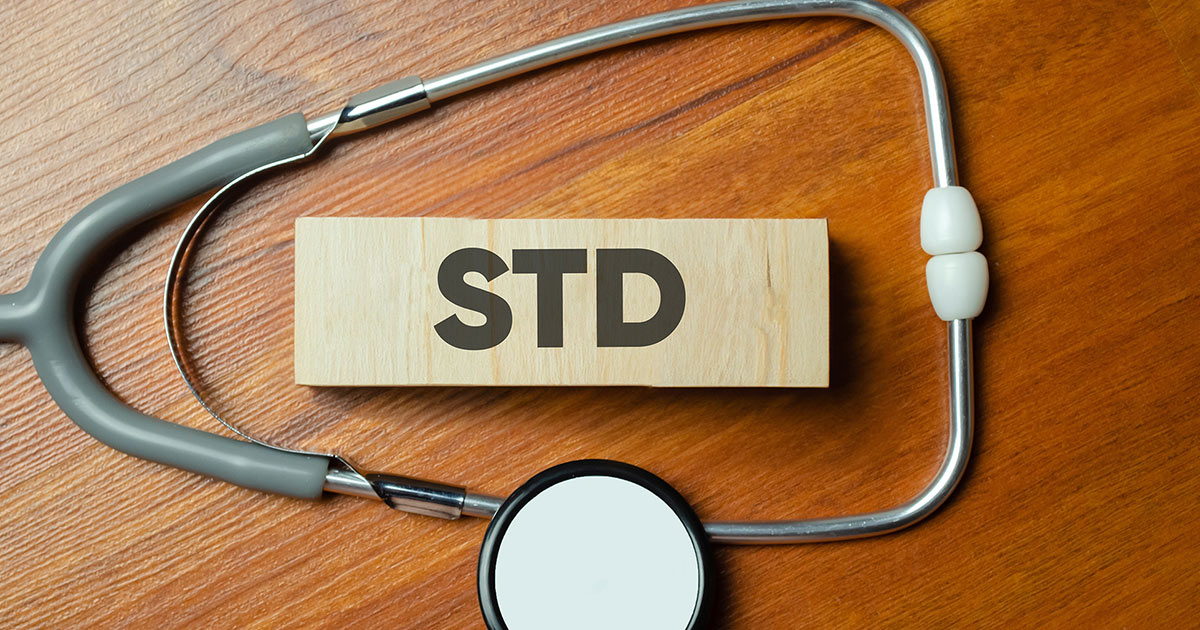 Foto von Holzblöcken, worauf die Buchstaben STD abgebildet sind, umgeben von einem Stethoskop. 