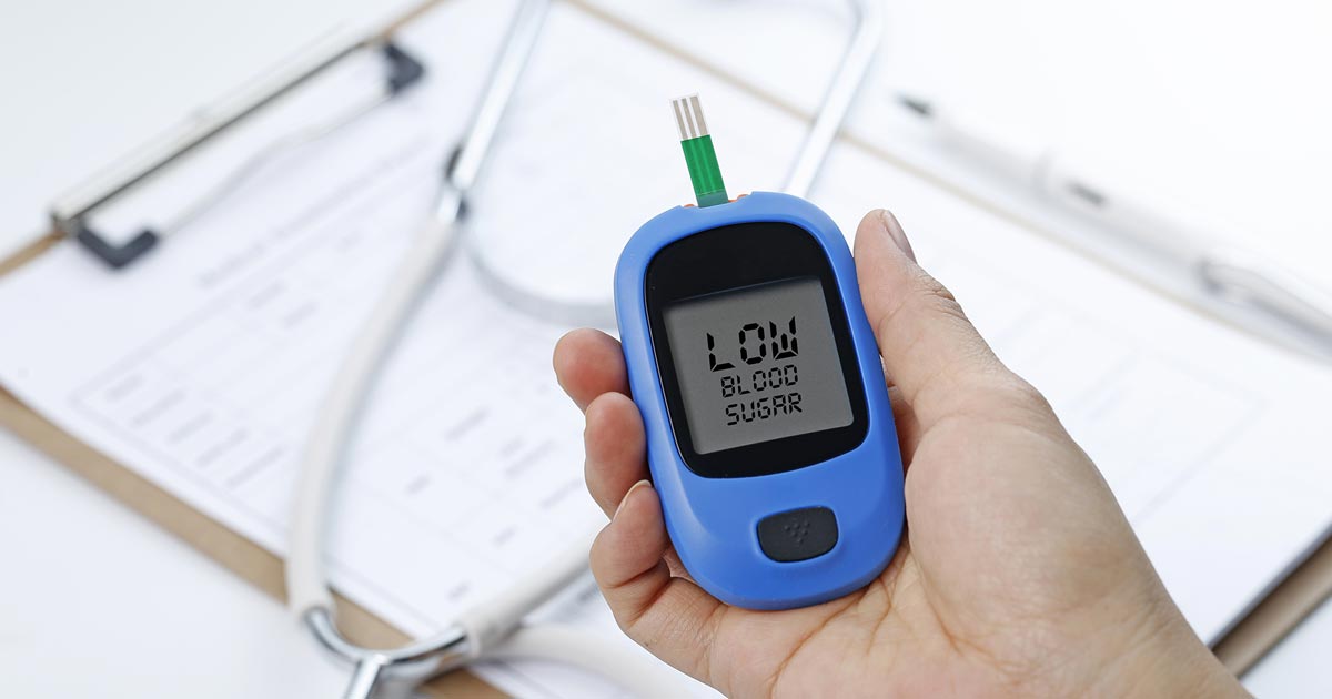 Person hält Blutzuckermessgerät in der Hand, auf dem „niedriger Blutzucker“ steht.