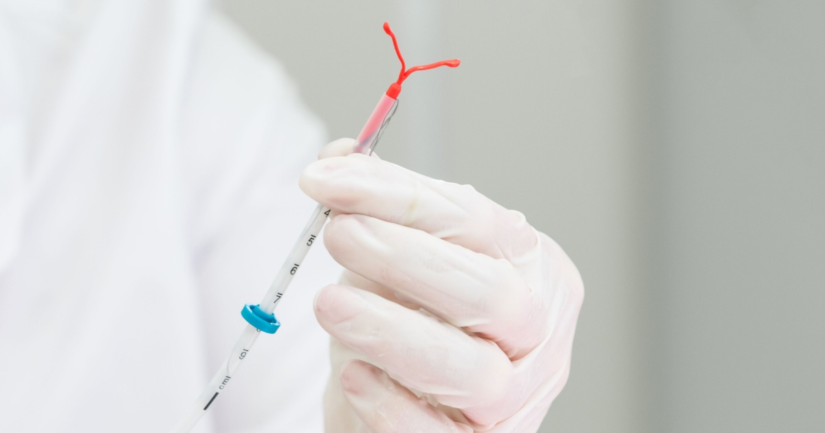 En læge, der holder et intrauterint system