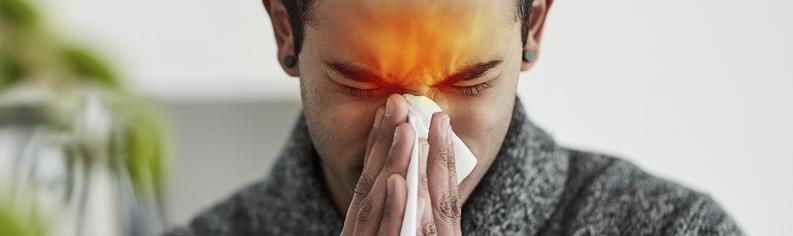Ung mand med tilstoppet næse, der puster næse