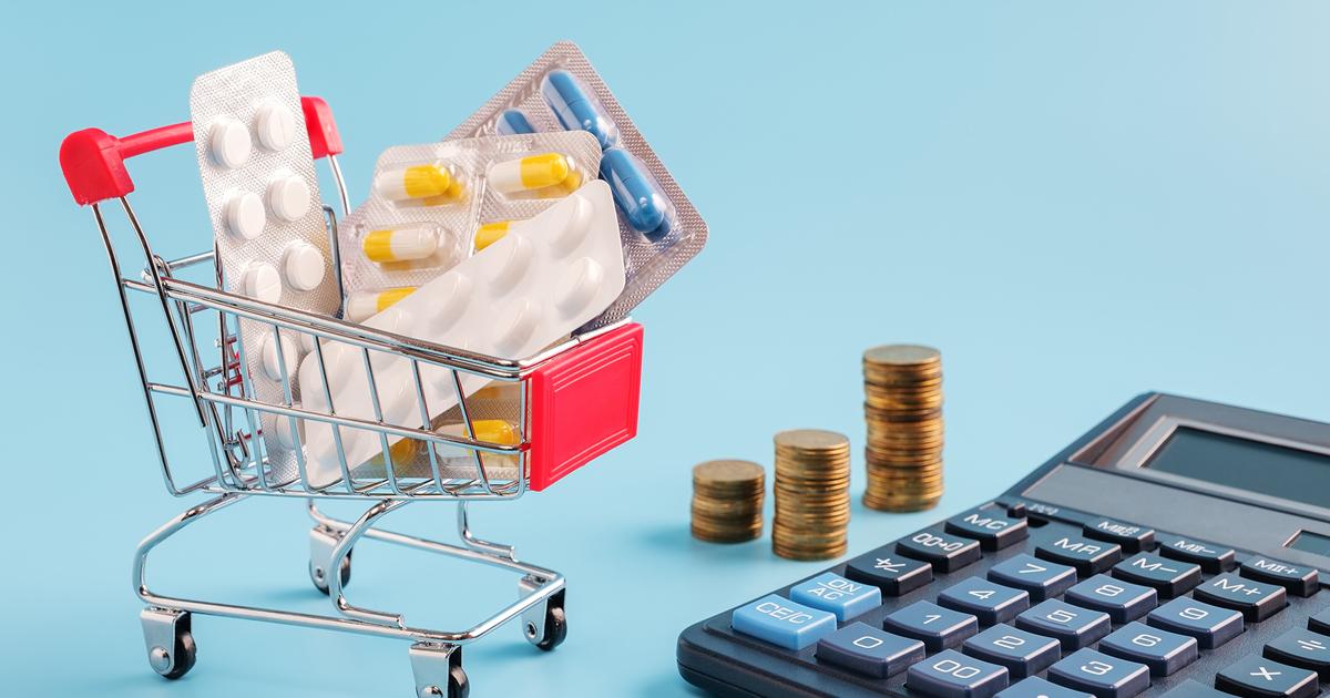 Indkøbsvogn fyldt med tabletter ved siden af en lommeregner og mønter.