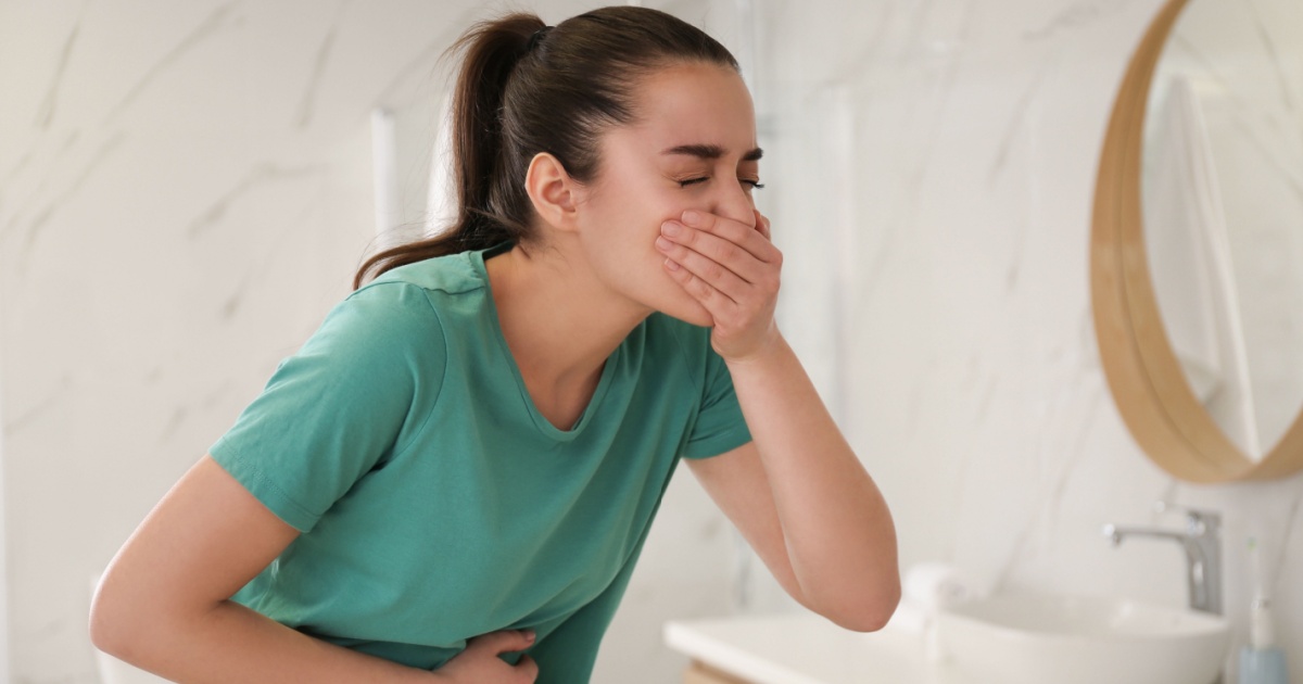 Billede af en kvinde der har kvalme, der holder munden