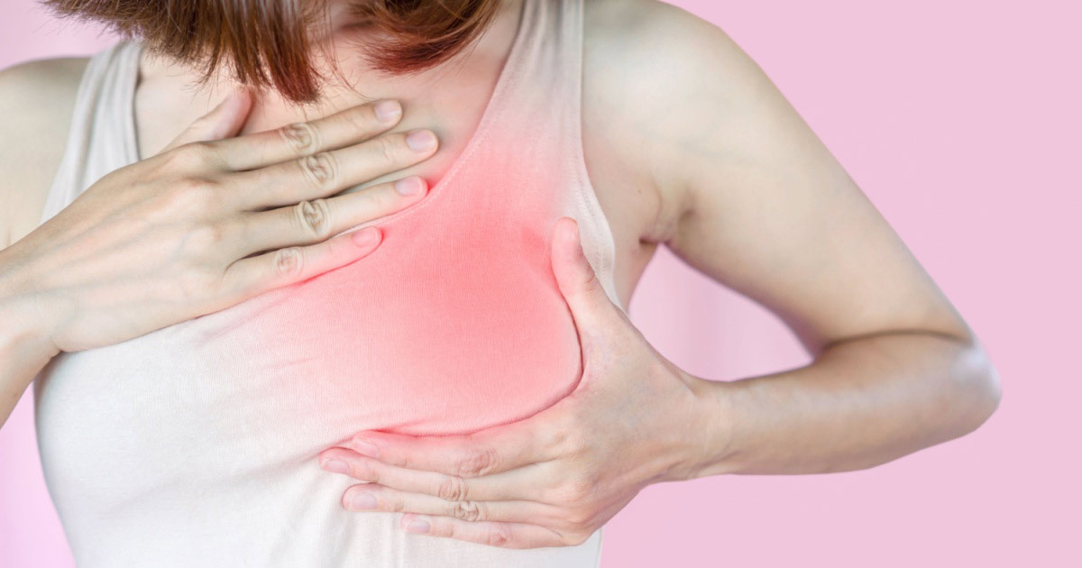 A woman wearing a white tank top with her breast area marked in red to signal pain. 