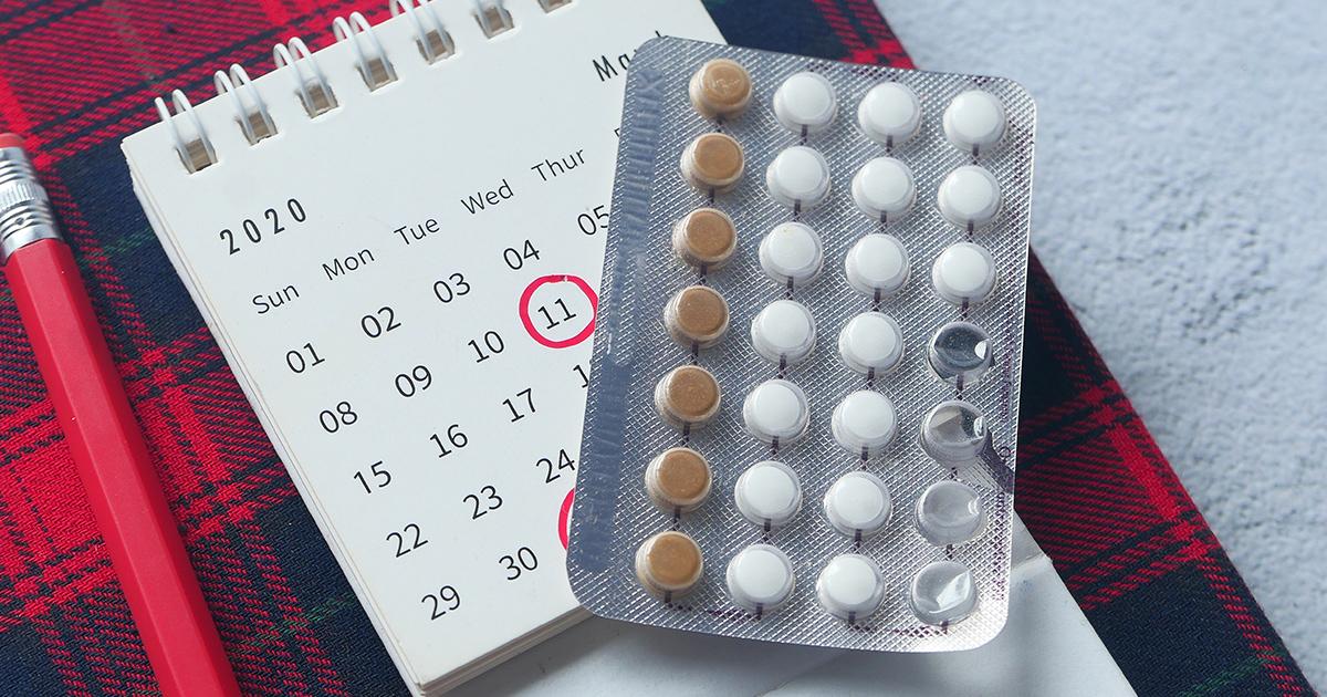 Combined pill pack with a calendar on top of a material with plaid (tartan) pattern