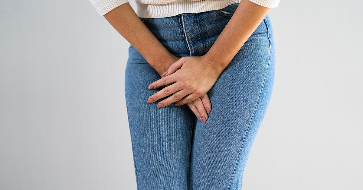  Close up of woman clutching jeans with urinary incontinence.