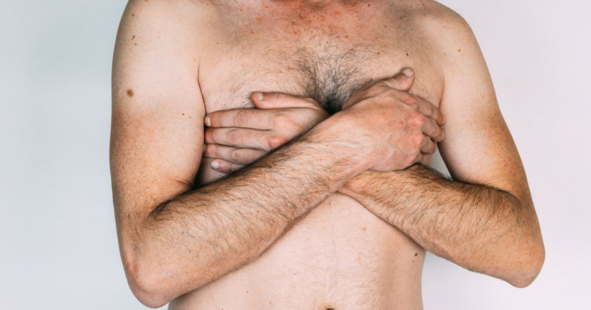 Close-up of man covering his chest shirtless.