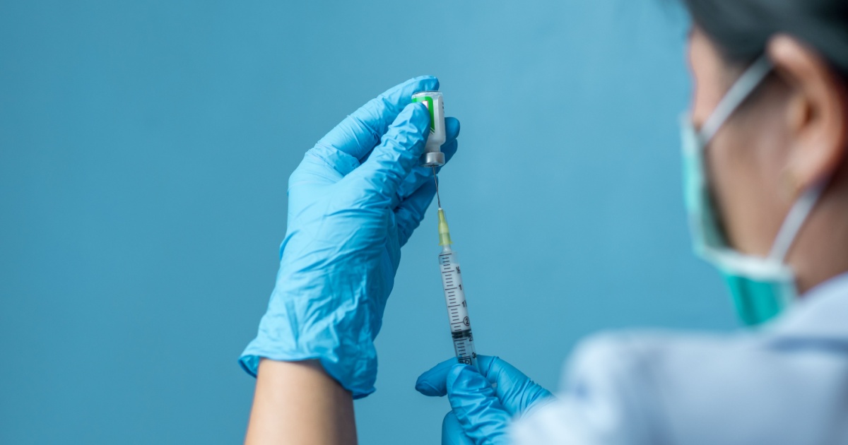 A female doctor wearing gloves preparing an injection.