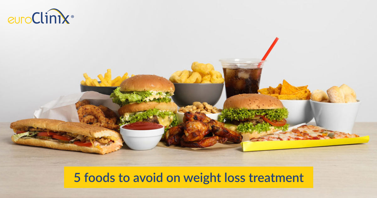 Selection of unhealthy foods and drinks on a grey background.