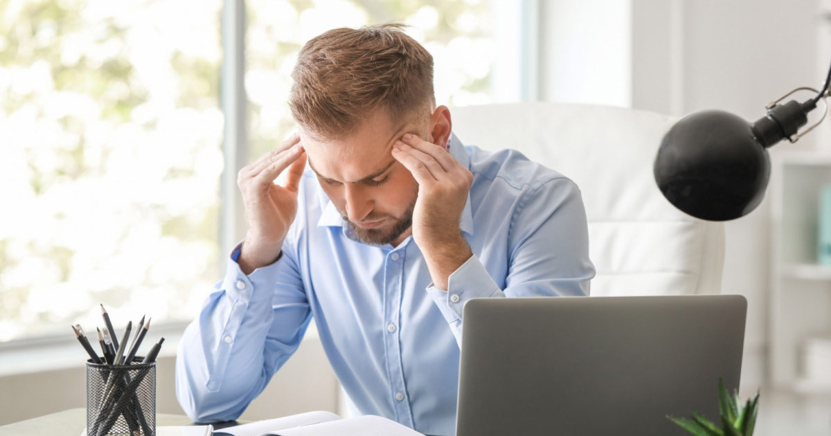 image of a young man in an office with a headache