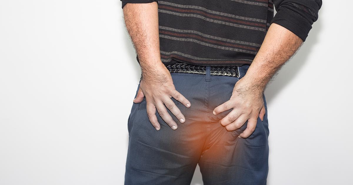 Man holding his trousers in pain with haemorrhoids. 