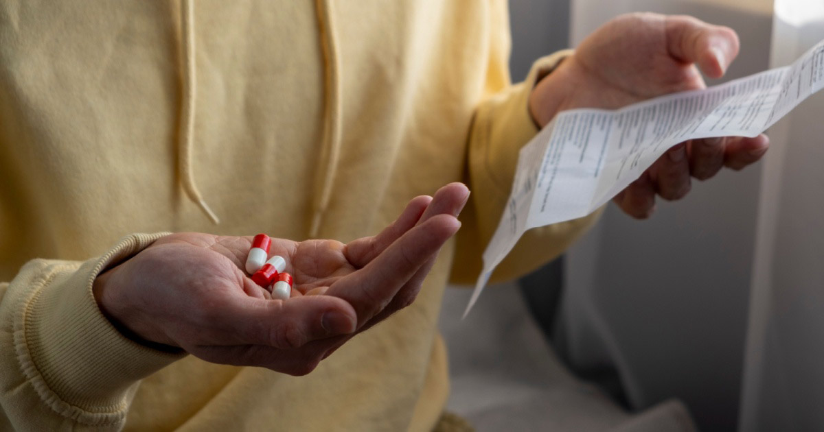Close-up of man reading patient leaflet with medication.