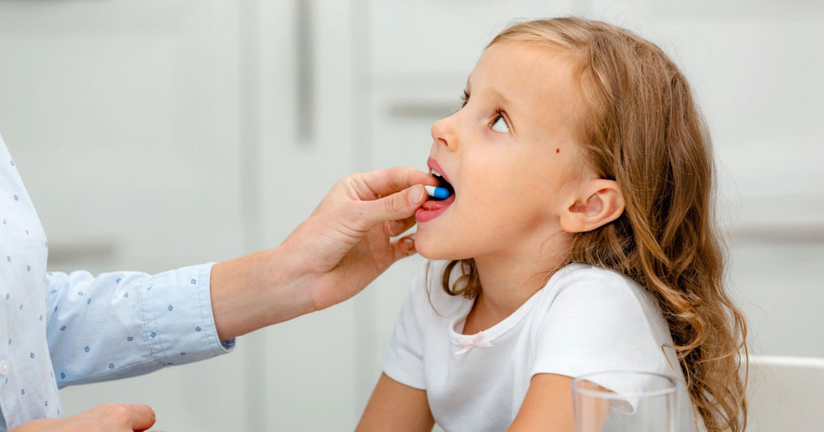 Image of a parent giving a child medicine