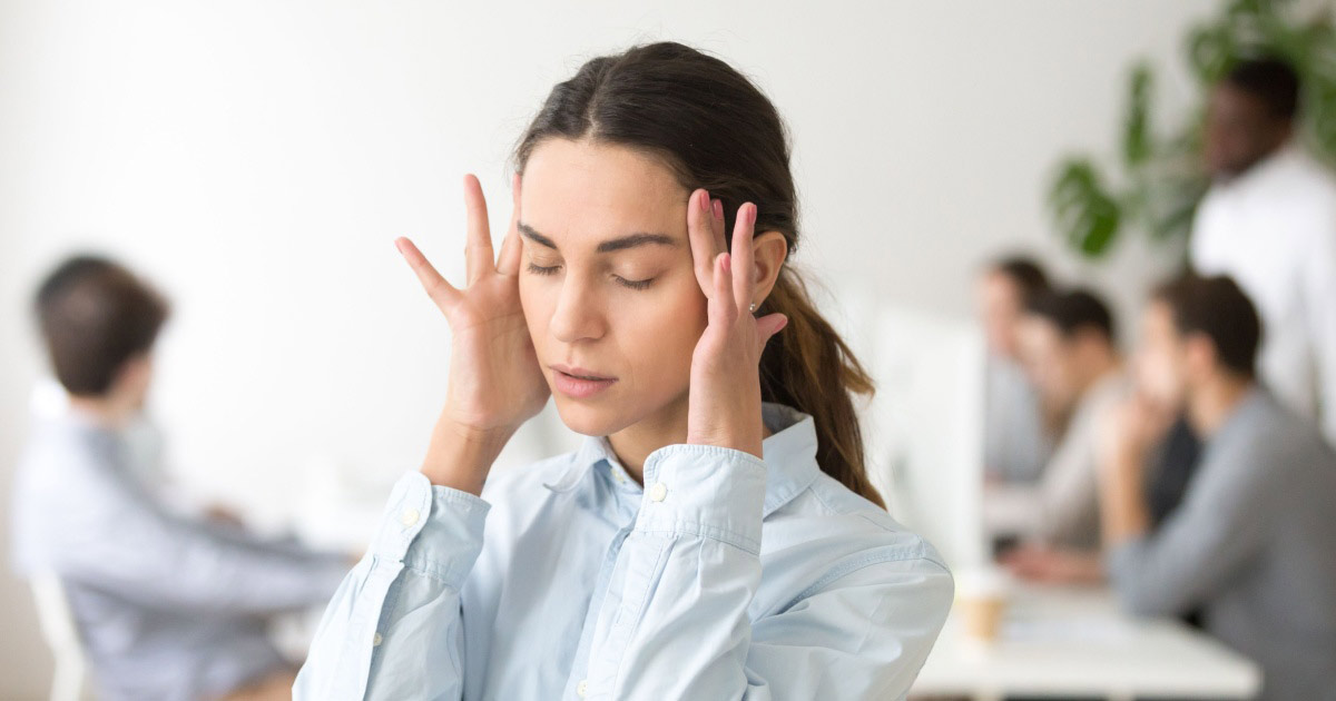 Young woman holding her temples due to a painful headache.