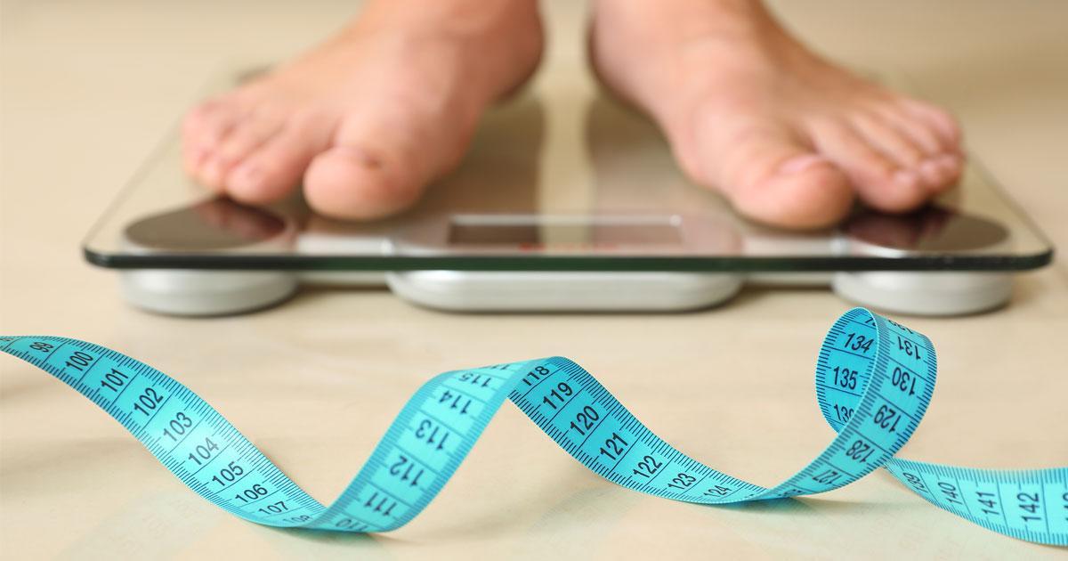  A person standing on scales next to a tape measure