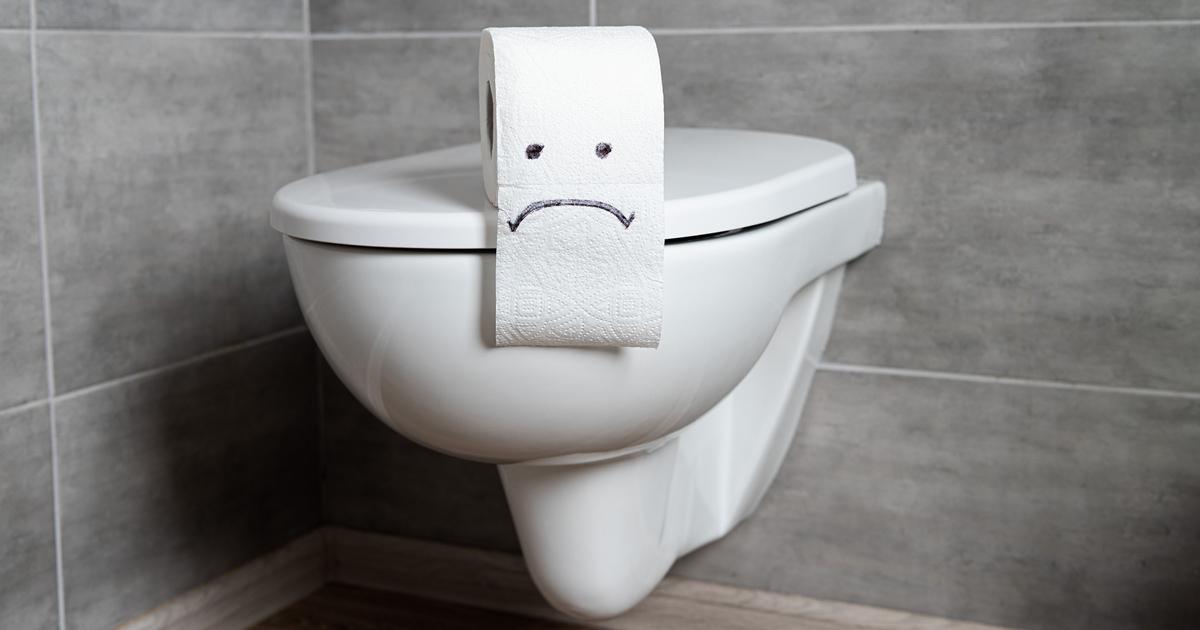 Toilet paper roll with a sad face on a toilet.