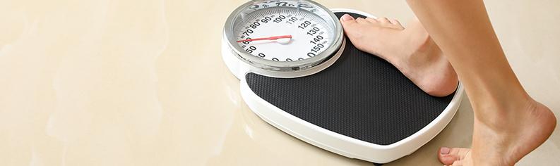 Close up of a woman's feet stepping on a scale.