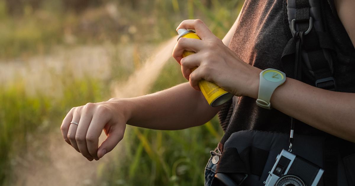 A woman spraying mosquito repellent on her arm