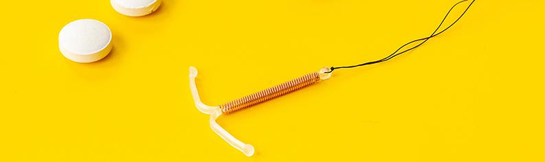 Kuparikierukka ja kolme ehkäisypilleriä keltaisella taustalla