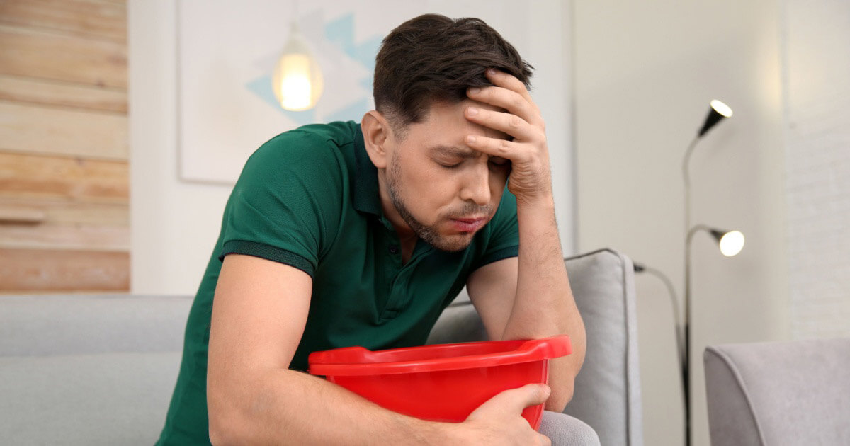 Nuori mies istuu sohvalla pahoinvoivan näköisenä.