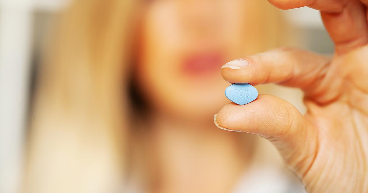 Femme tenant la pilule bleue de Viagra. 
