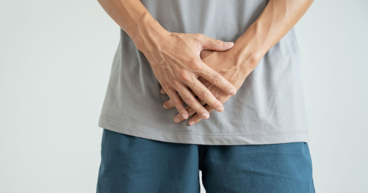 Gros plan d'un homme avec les mains sur l'entrejambe.