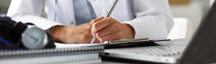 Médecin généraliste écrivant à son bureau.