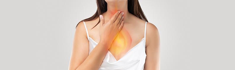 Une femme touchant sa gorge à cause de la douleur du reflux acide