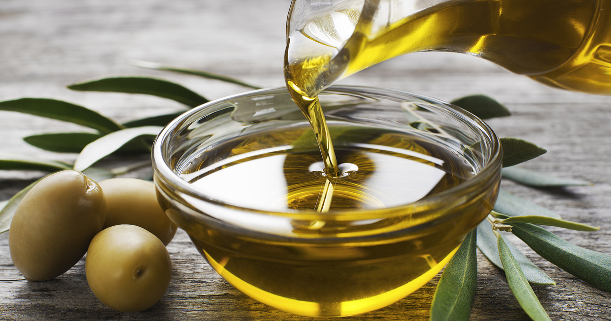 En flaske olivenolje helles i en liten, klar form