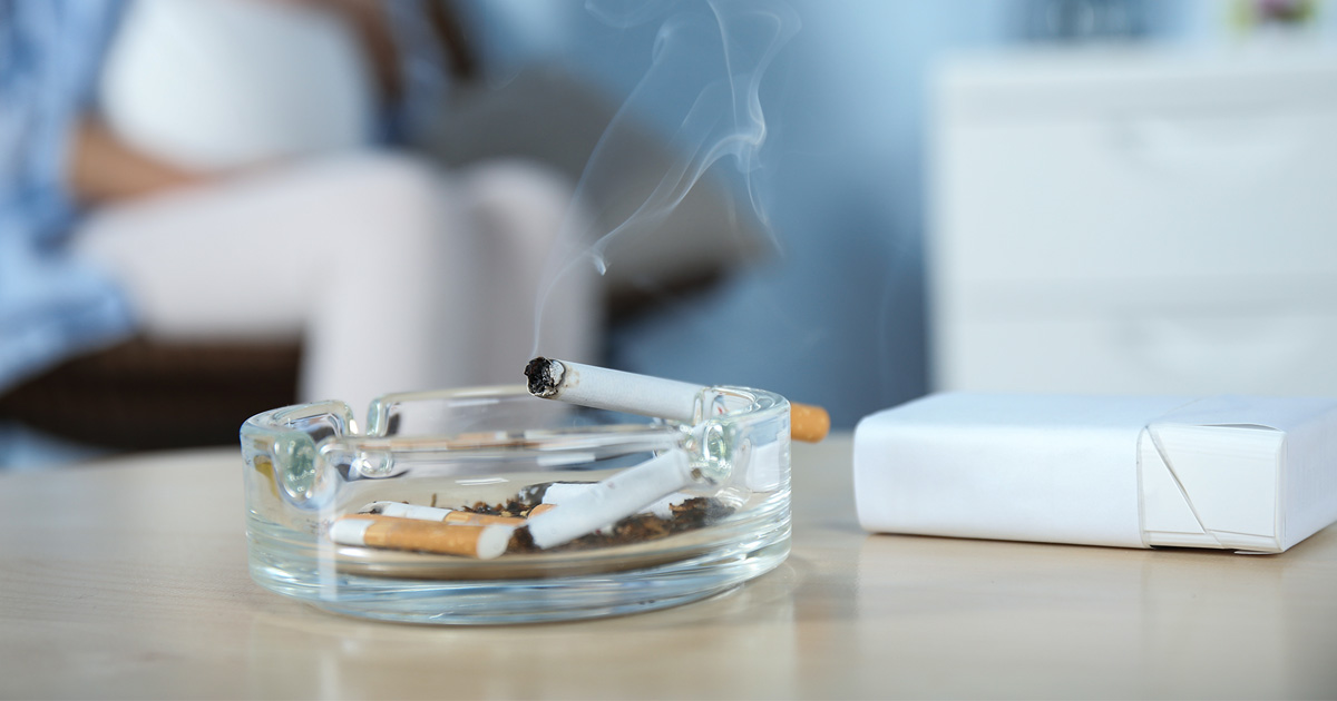 sigaretter i et askebeger i nærheten av en gravid kvinne