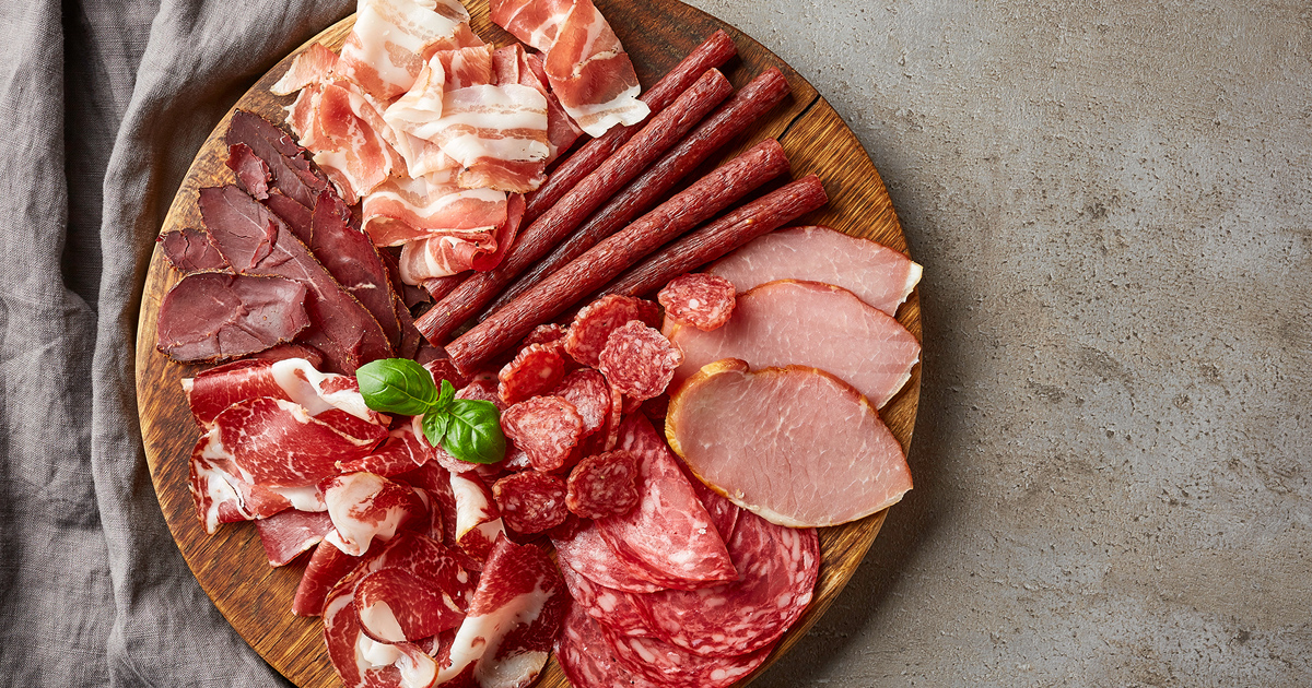 Et utvalg av røkt kjøtt på et skjærebrett av tre