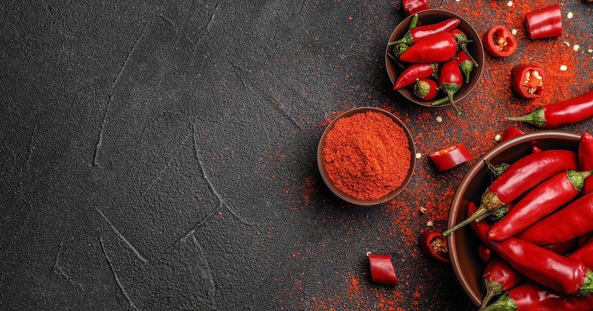 Skåler med chili og kvernet chilipepper på en grå skifer.