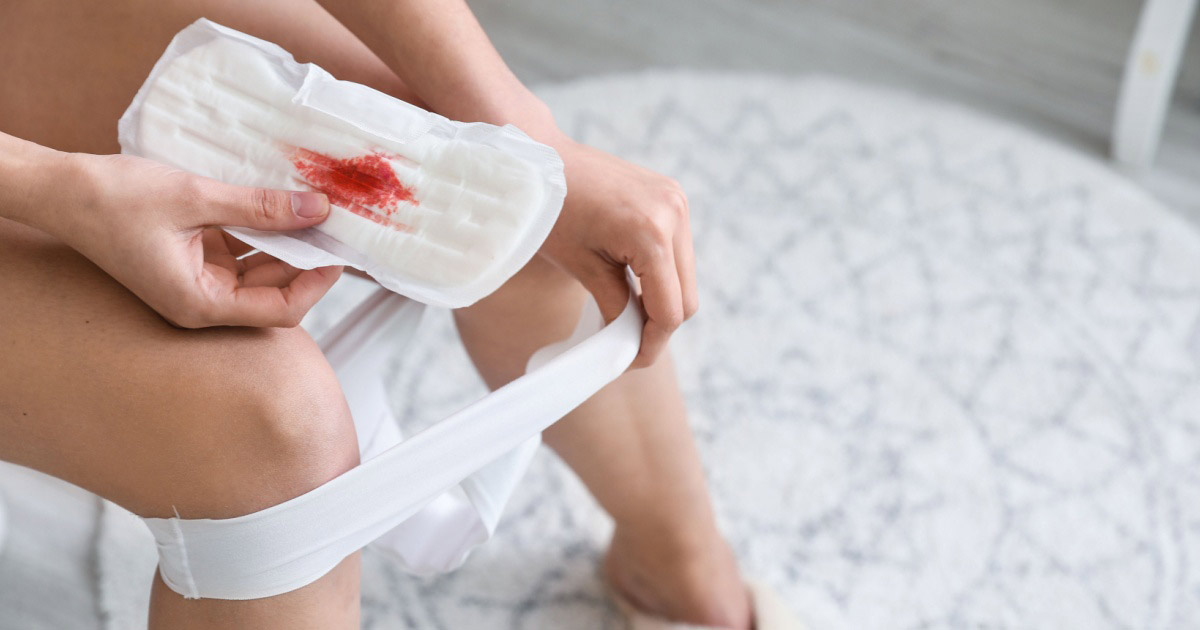 Kvinne som holder en menstruasjonspute som er flekket med en liten mengde blod.