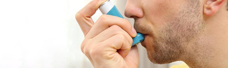 mężczyzna używający niebieskiego inhalatora na astmę