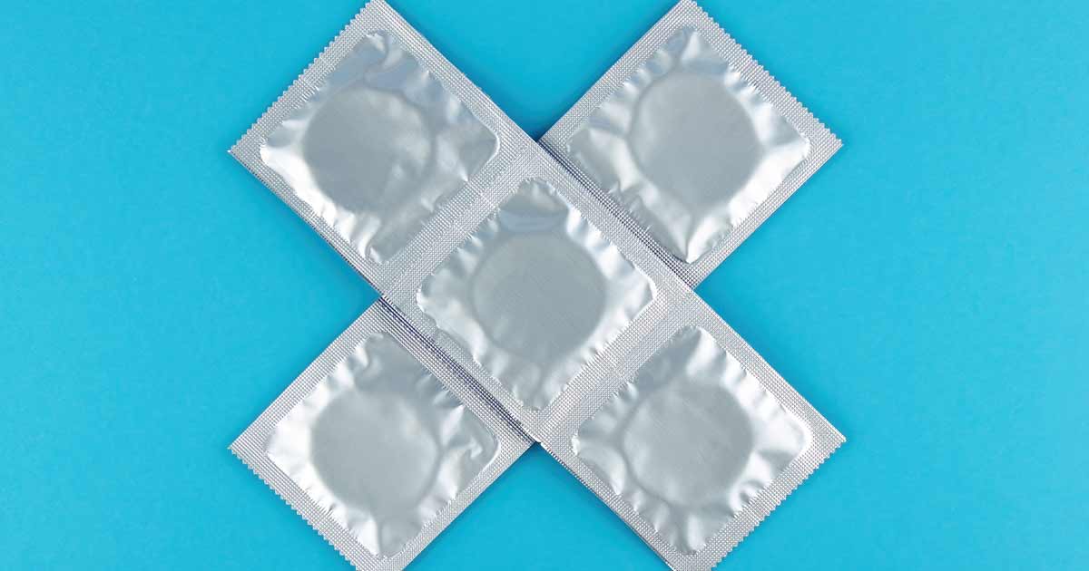 Invólucros de preservativos com a forma de um 'x' sobre um fundo azul.