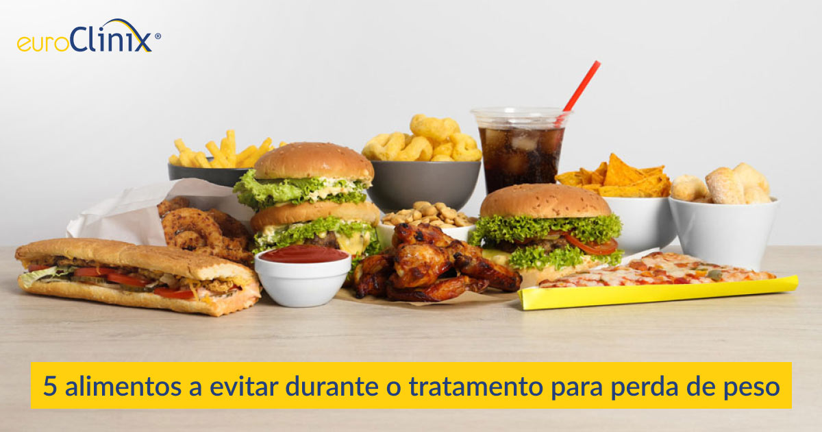 Seleção de alimentos e bebidas pouco saudáveis sobre um fundo cinzento.