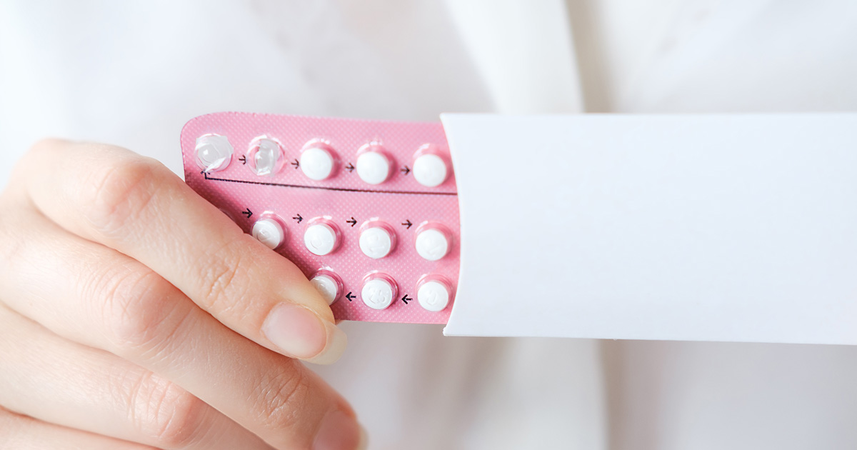 Uma mulher a segurar um blister de pílulas contraceptivas hormonais